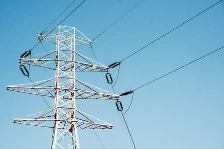 Transmission tower background. High voltage electricity pylon. Metal construction and blue sky....
