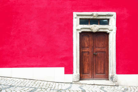 Old wooden door on a red wall, in the city of Lisbon, Portugalの写真素材
