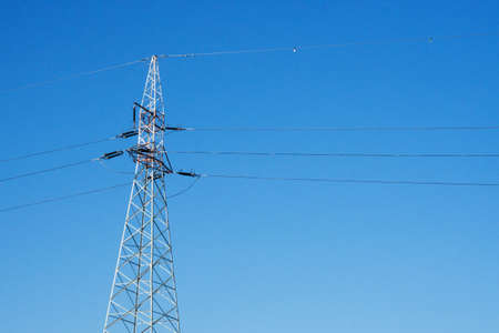 High voltage power lines on blue sky background. Electricity distribution station.