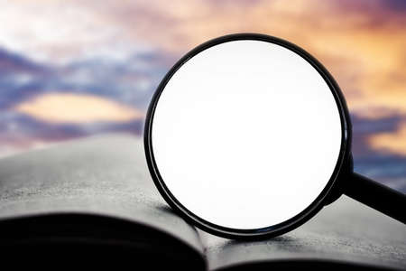 Magnifying glass on the book with sunset sky background. Education conceptの写真素材
