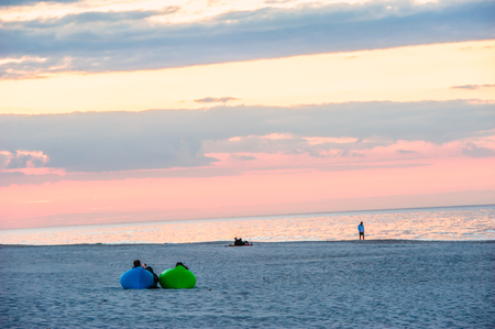 two people relaxing on the mattresses during the sunset by the seaの写真素材