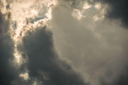 black storm clouds illuminated by the rays of the sunの写真素材