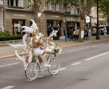BERLIN, GERMANY - JUNE 21, 2014: Christopher Street Day. Crowd of people Participate in the parade celebrates gays, lesbians, bisexuals and transgenders. Prominent in the image, elaborately dressed participant riding bike, during Christopher Street Day Paのeditorial素材