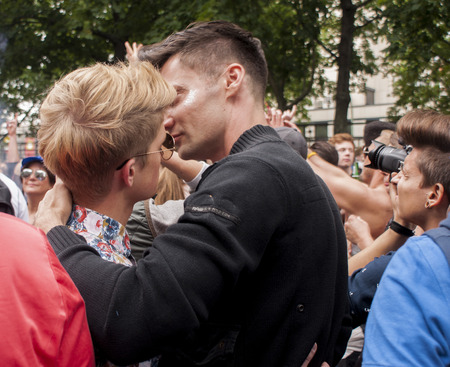 BERLIN, GERMANY - JUNE 21, 2014:Christopher Street Day.Unidentified gay couple cuddling during Gay pride parade.Crowd of people participate in the parade celebrates gays, lesbians, bisexuals and transgenders.のeditorial素材