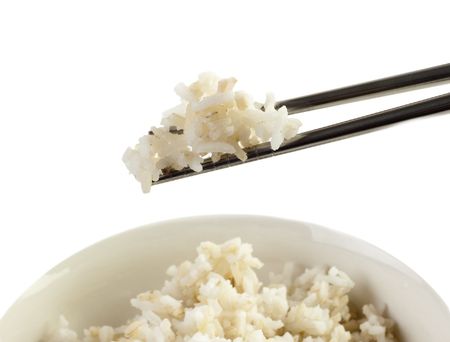 A bowl of cooked brown rice, in an Asian style bowl, with chopsticks isolated on white.の写真素材