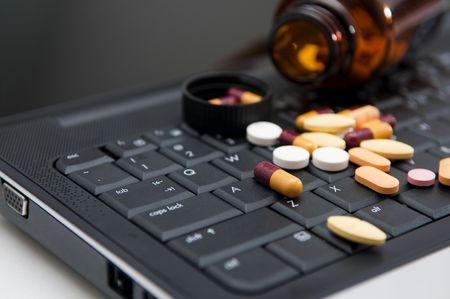 Pills on a laptop, work pressure concept.の写真素材