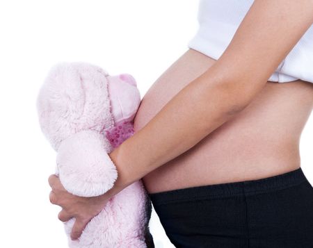 Woman holding a soft toy on her 8 months pregnant belly.の写真素材