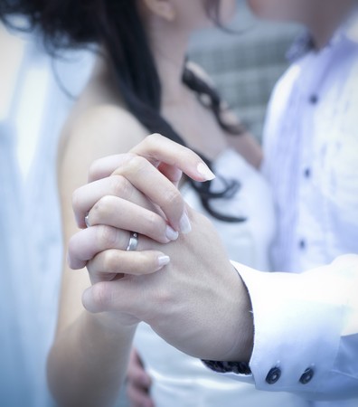A bride and groom kissing on their wedding day, focus on handsの写真素材