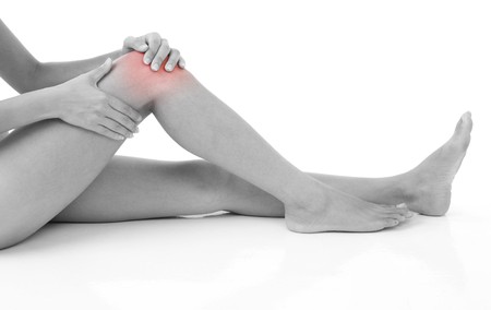 Woman holding on sore knee isolated on white.の写真素材