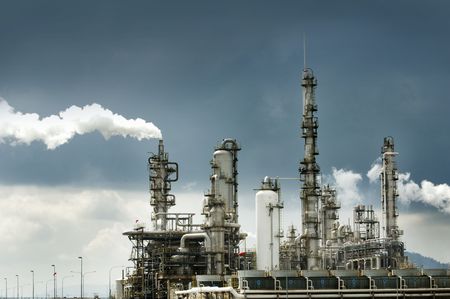 Oil refinery with smoke against moody sky