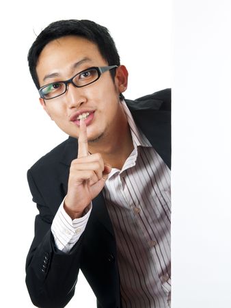 Asian man with blank board, finger on lipsの写真素材