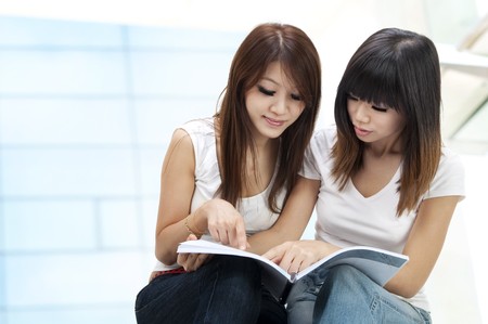 Two young student sitting outside school buildingの写真素材