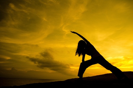 Silhouette of Woman Practicing Yoga (Warrior Pose)の写真素材
