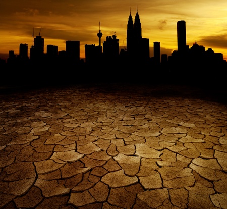 A city looks over a desolate cracked earth landscape in sunsetの写真素材