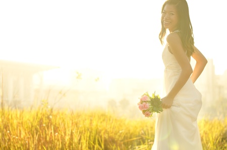 Asian bride at outdoor in a morning surrounding by golden sunlightの写真素材