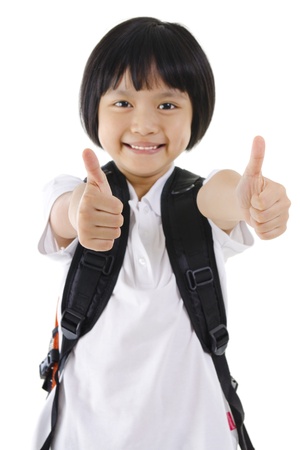 Thumbs up primary school girl with backpack on white backgroundの写真素材