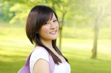 Asian adult student standing outdoor park, green tree backgroundの写真素材