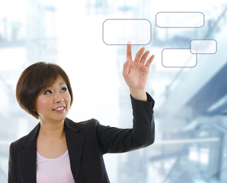 Mid adult Asian woman finger pressing on touchscreen monitorの写真素材