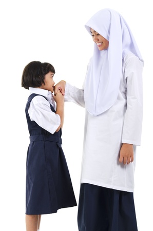 Young Southeast Asian Muslim girl  greeting to her elder sister over white backgroundの写真素材