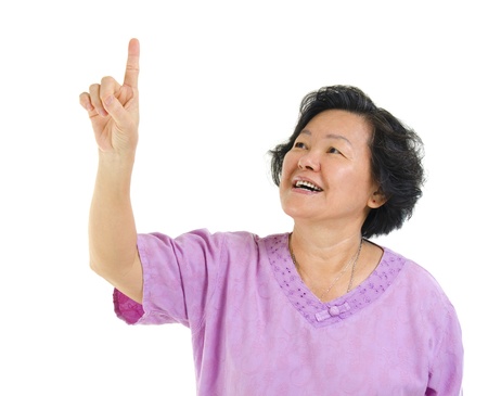 60s Asian senior woman pointing on transparent virtual screen button, over white backgroundの写真素材