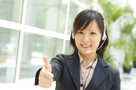 Friendly Customer Representative with headset thumb up during a telephone conversation.の写真素材