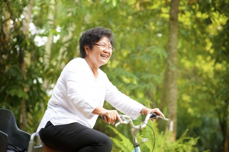 60s senior Asian woman riding on bicycle outdoor with great funの写真素材