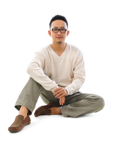 Full body Asian man sitting on white floorの写真素材