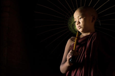 A Young novice monk holding an umbrellaの写真素材
