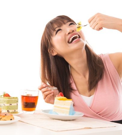 Smiling Asian woman eating cakes in the living room in her house Smiling Asian woman eating cakes in the living room in her house