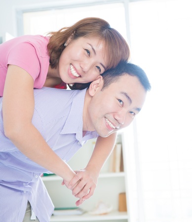 Asian couple piggyback ride indoorの写真素材