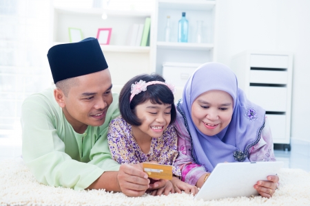 Southeast Asian family online shopping with credit card at home. Muslim family living lifestyle.の写真素材