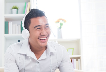 Attractive Southeast Asian man listen mp3 at homeの写真素材