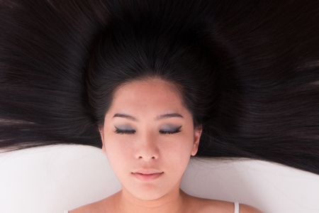 Close up beautiful young Asian girl lying on white with scatter hairの写真素材
