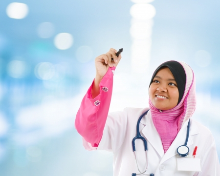 Southeast Asian Muslim medical student sketching on transparent screen, hospital blue backgroundの写真素材