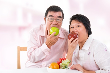 Southeast Asian mature couple eating fruits at home.の写真素材