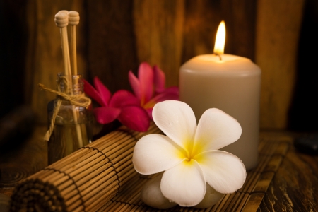 Low light spa setting indoor with candle, frangipani and aroma set.の写真素材