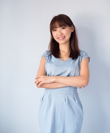 Portrait of cute Asian woman smiling wearing blue dress isolated on blue background. Asian female model.の写真素材