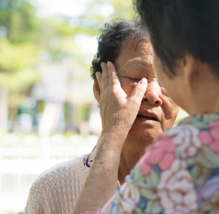 Candid shot of a mature woman consoling her tearful crying old mother at outdoor natural park. の写真素材