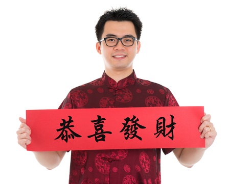 Asian man with Chinese traditional cheongsam or tang suit holding couplet, the Chinese word means congratulations and best wishes for a prosperous New Year.  Male model isolated on white background.の写真素材