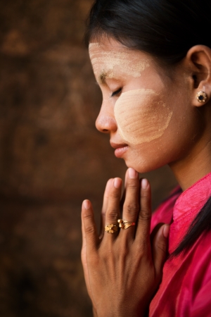 Beautiful traditional Myanmar girl is praying inside temple.の写真素材