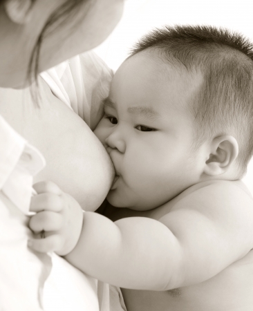 Mother and baby. Close up Asian mother breastfeeding baby boy in sepia tone.の写真素材
