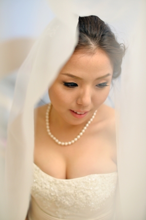 Beautiful Asian bride smiling under the veil on wedding day.の写真素材
