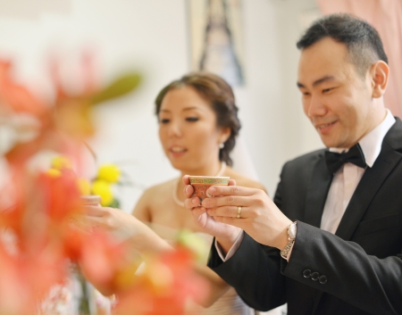 Traditional Chinese wedding tea ceremony, bride and groom, focus on hand and teacup.の写真素材