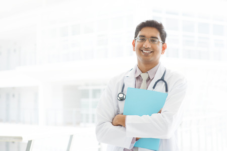 Portrait of a smiling Asian Indian male medical doctor standing inside hospital, holding file folder.の写真素材