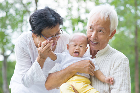 Asian crying baby comforted by grandparents at outdoor gardenの写真素材