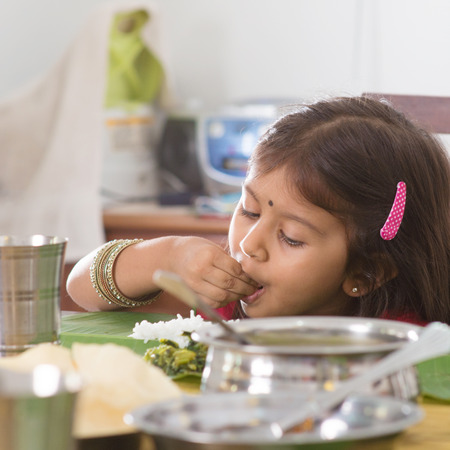 Indian family dining at home. Candid photo of Asian child self feeding rice with hand. India culture.の写真素材
