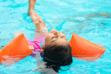 Indian child learning swimming in pool. Asian kid in swimmer class with float bands.の写真素材