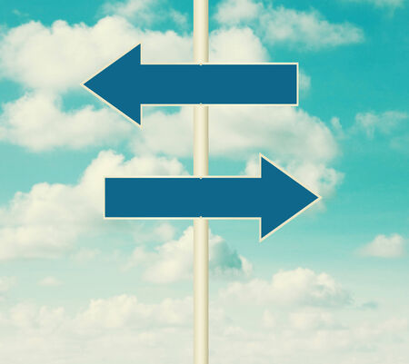 Two blank road signs pointing in opposite directions, blue sky background in vintage style.