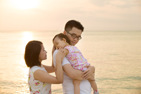 Portrait of young Asian family outdoor beach vacation, during summer sunset, natural sunlight. の写真素材