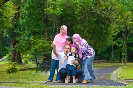 Happy Southeast Asian family outdoor lifestyle at nature green park, pointing and looking away.の写真素材